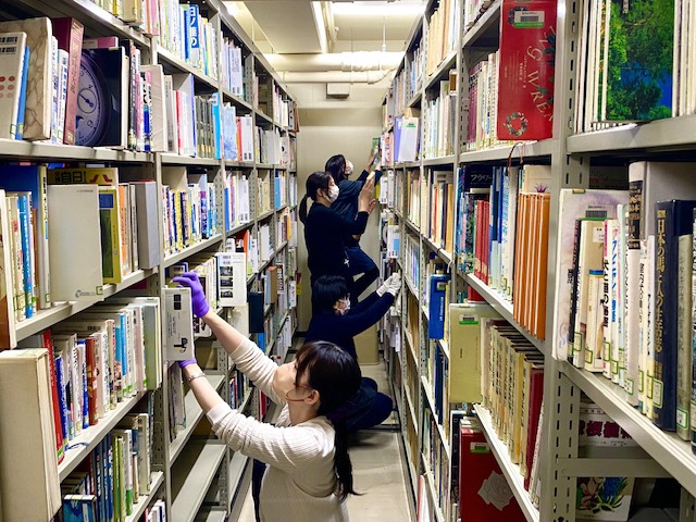 図書館の本棚の間で本を探している人々の様子