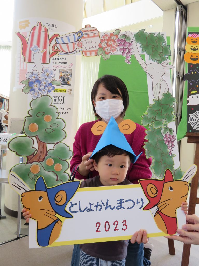 子供が色とりどりの帽子をかぶり「くしゃんまつり2023」と書かれた看板を持っている画像