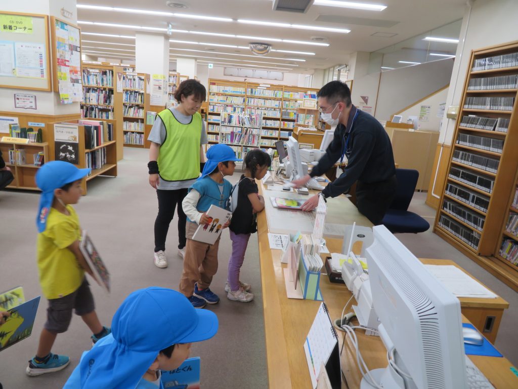 子どもたちが図書館のカウンターで本を返却している様子。