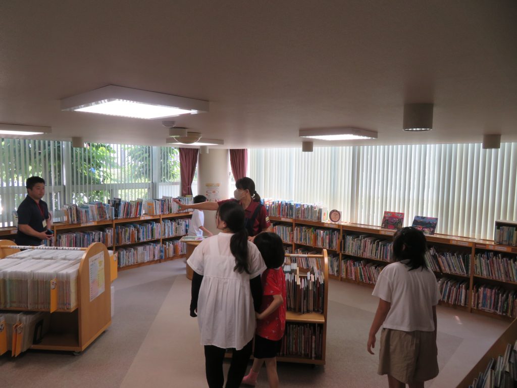 図書館の中で数人の子供たちが本棚の周りで活動している様子。