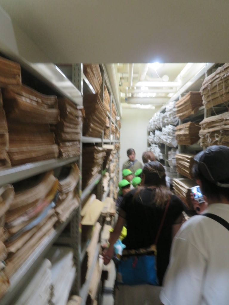 人々が棚に並んだ商品に囲まれた通路を歩いている様子を捉えた画像。