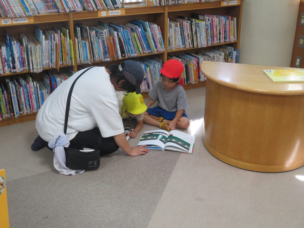 図書館で本を見ている子供と大人がいるシーン。