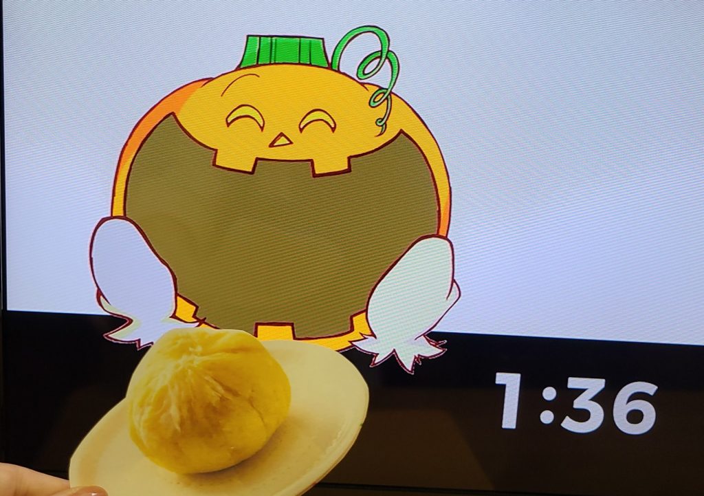 画面に笑顔のカボチャのキャラクターが描かれており、手前には丸い物体がある。