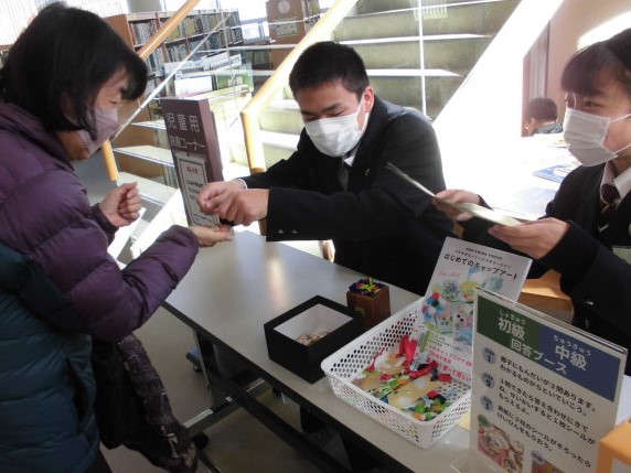 カウンターで取引をしている人々と掲示物が写っている画像。