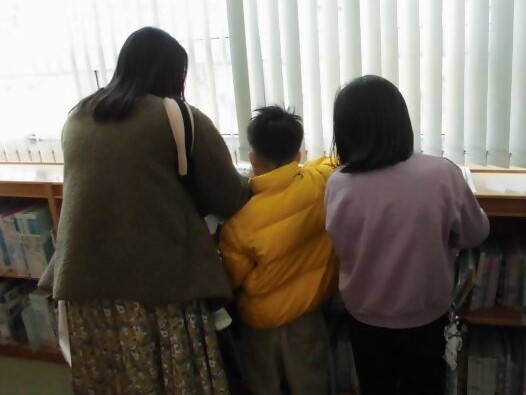 窓の外を見つめる大人と子供の後ろ姿が写っている画像