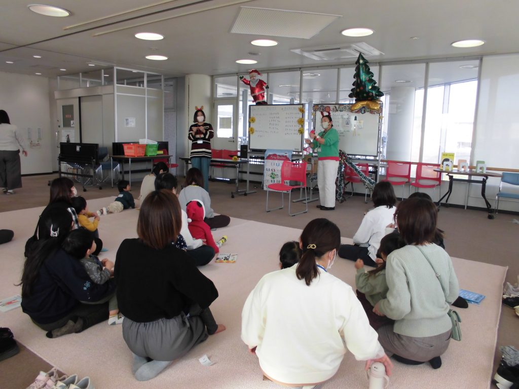 教室で座っている子供たちが前で話している大人を見ている様子の画像。