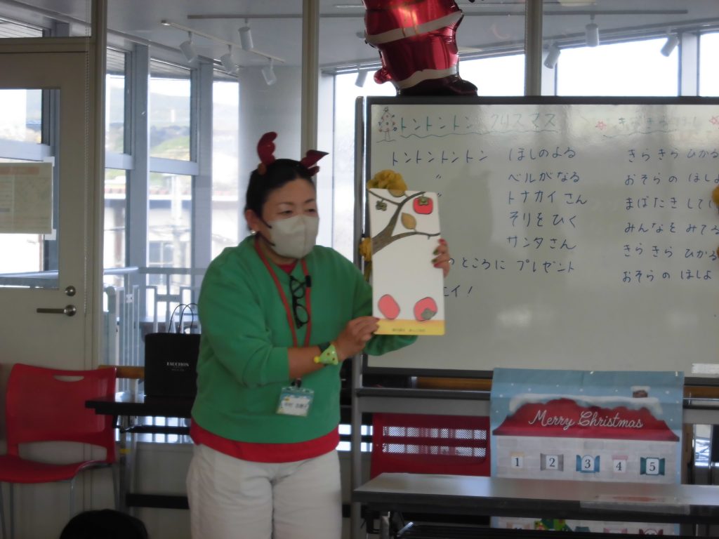 教室で教材を持っている人物がホワイトボードの前に立っている画像