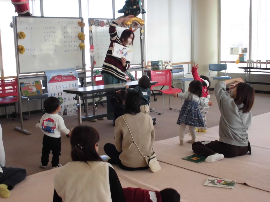 子供たちが活動している室内で、大人がパフォーマンスをしている様子。