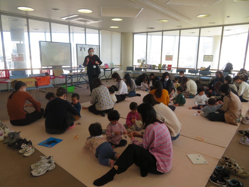 子供たちと大人が集まって活動している室内の風景。