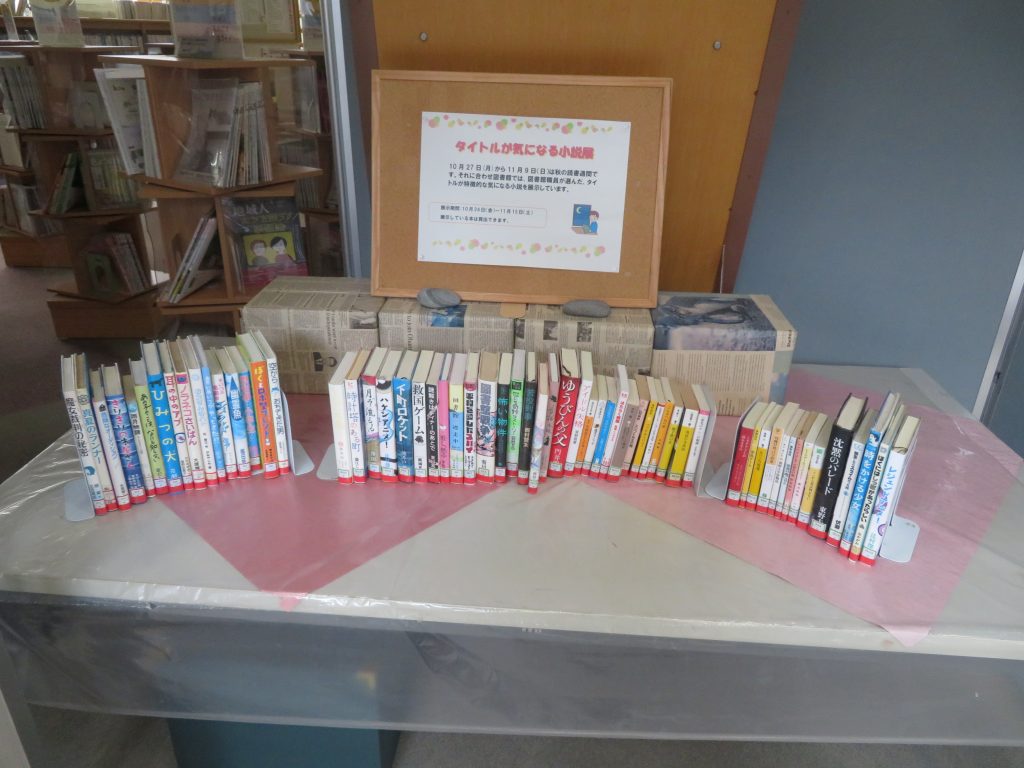 本が並べられたテーブルとその後ろに掲示されているサインが写っている画像。