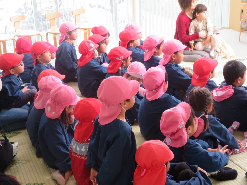 子供たちがピンクの帽子をかぶって座っている様子