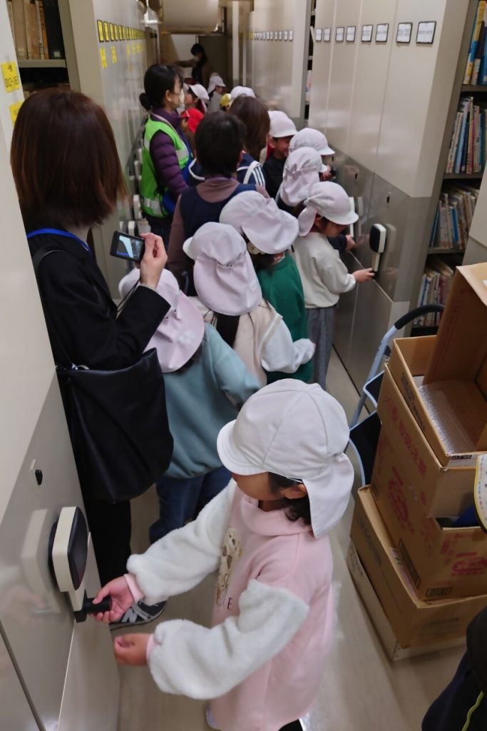 子供たちが帽子をかぶり、廊下で何かを操作している様子の画像です。