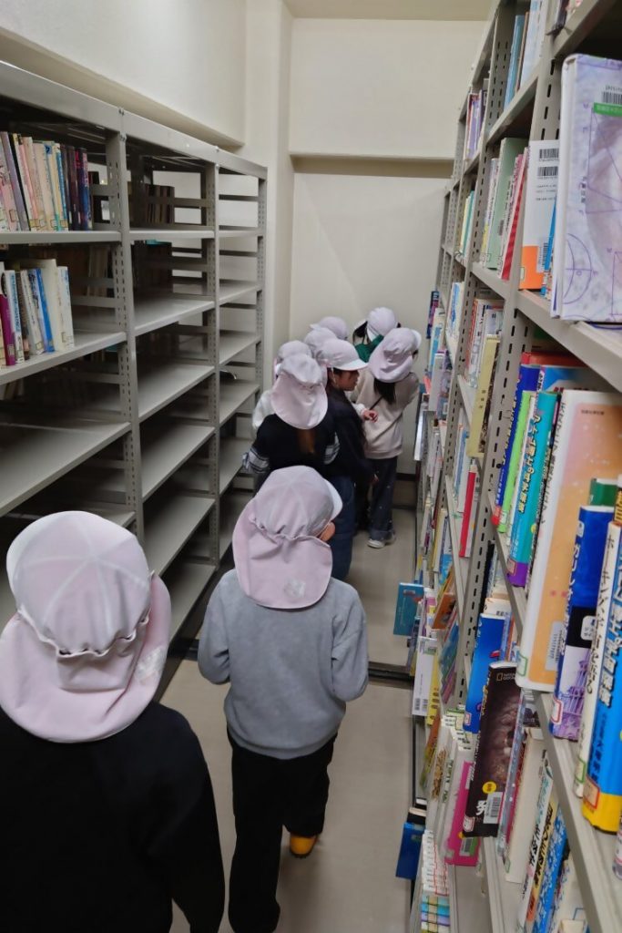 本棚の間を歩く子供たちが帽子をかぶっている様子。