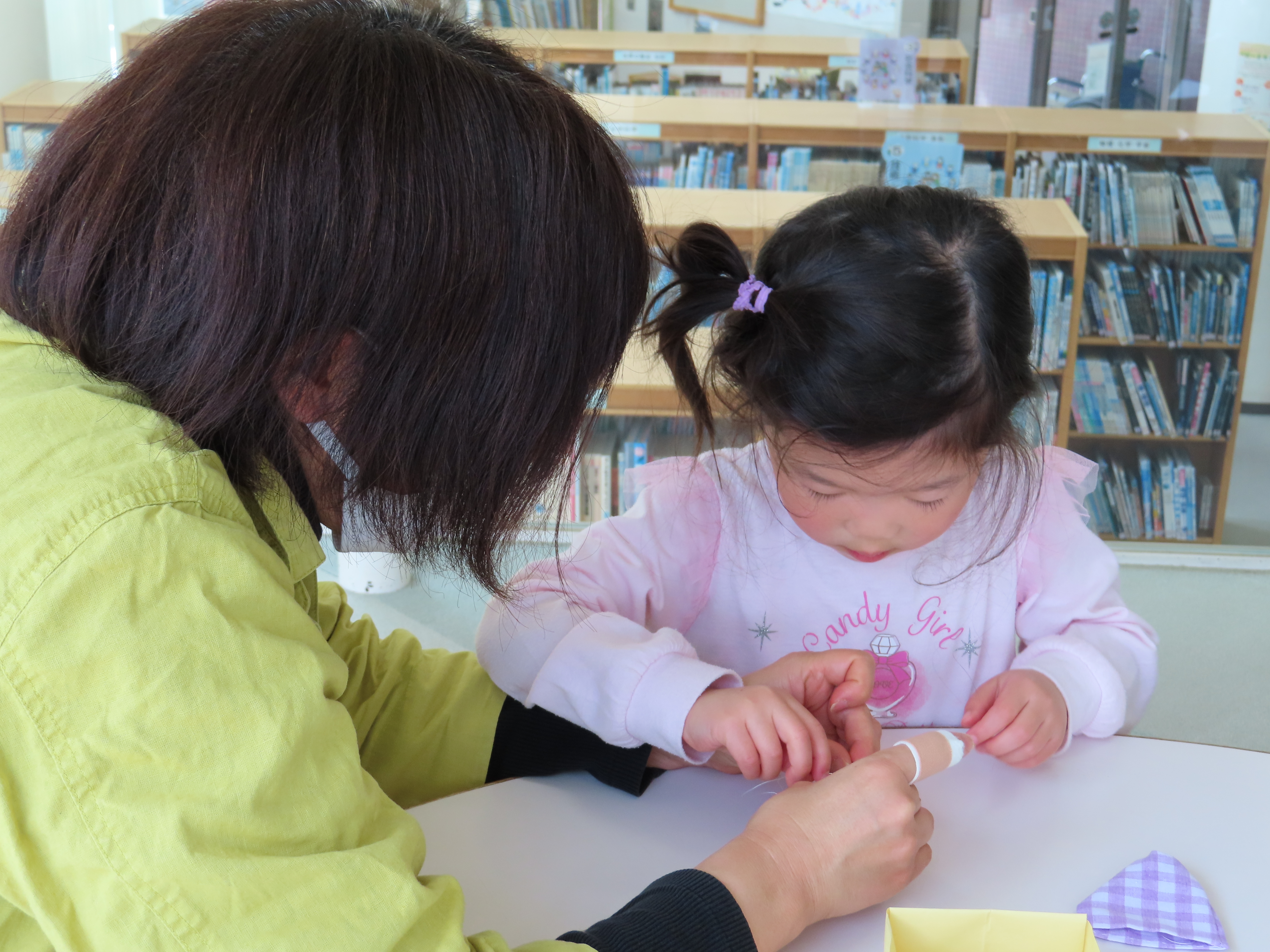 大人が子どもの手を支えながらお手玉作りを手伝っている光景