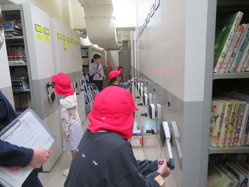 子供たちが赤い帽子をかぶり、ロッカーの前で何かを操作している様子が描かれた画像。