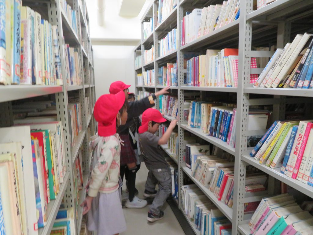 図書館の本棚の前で本を探している子どもたちの様子