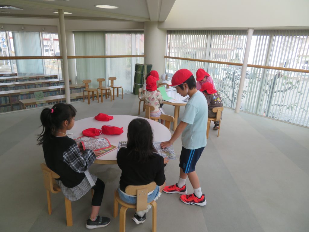 子供たちが赤い帽子をかぶり、室内のテーブルで何かに取り組んでいる様子。