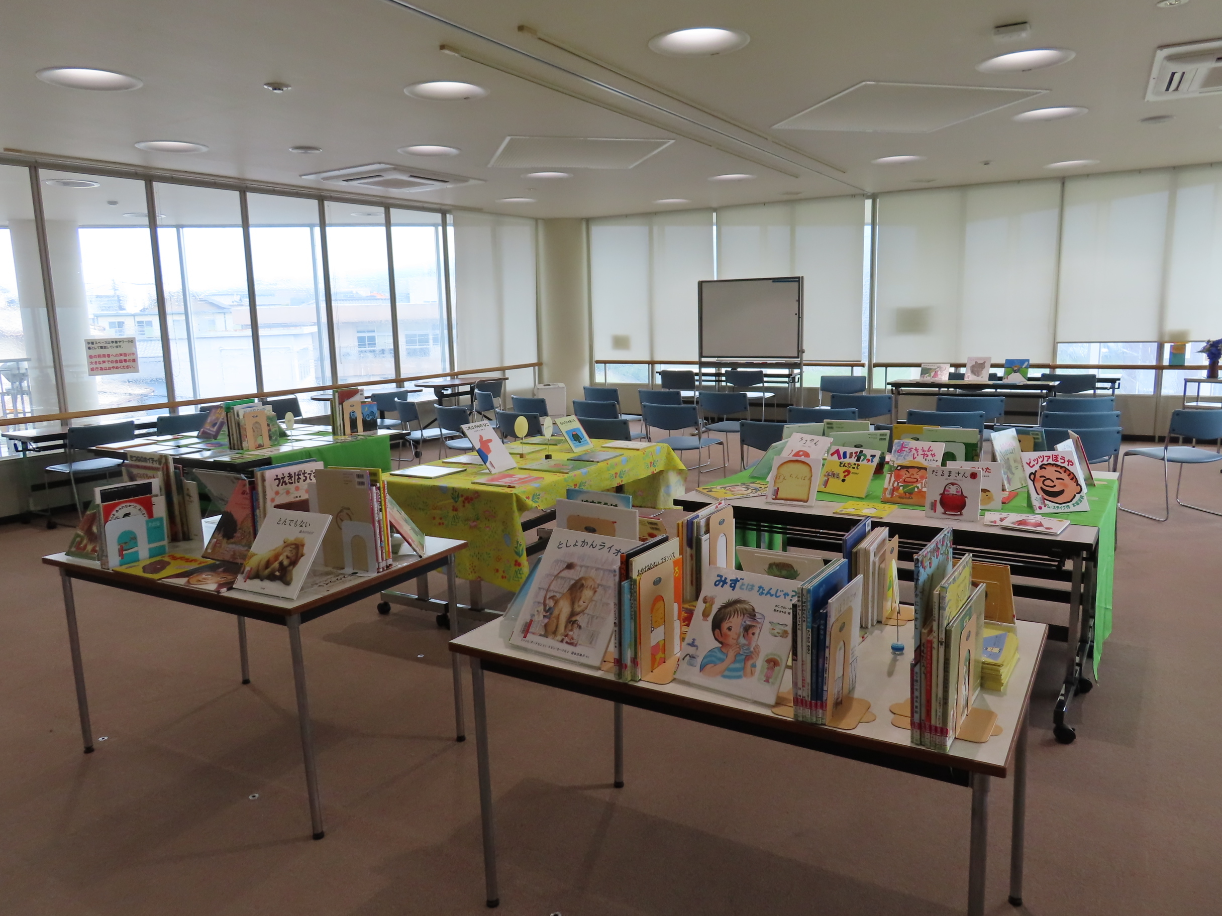 展示室に複数の机が並べられ子ども向けの絵本や展示物がテーブルに並んでいる