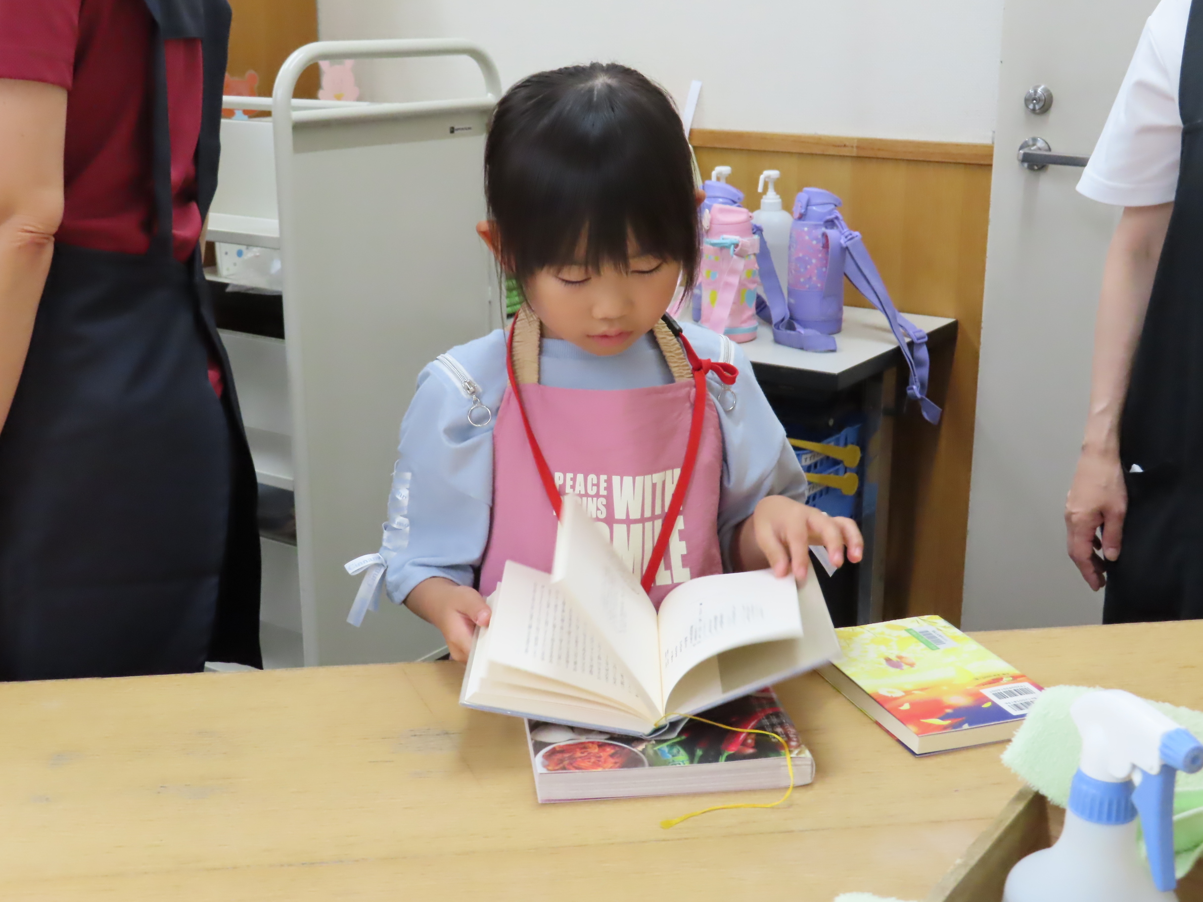 テーブルの上で返却本をめくる幼い女の子