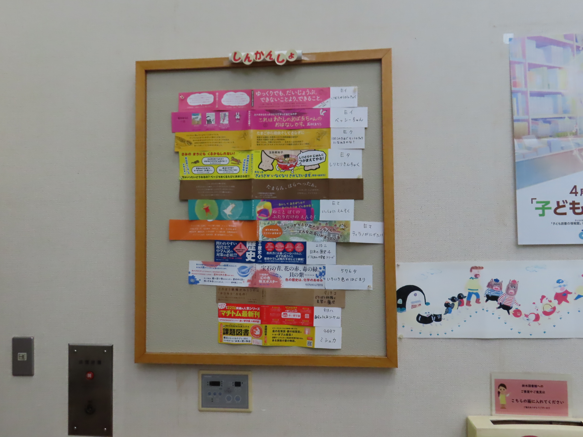 色とりどりの案内が木枠の掲示板に縦に並べて貼られている壁の様子