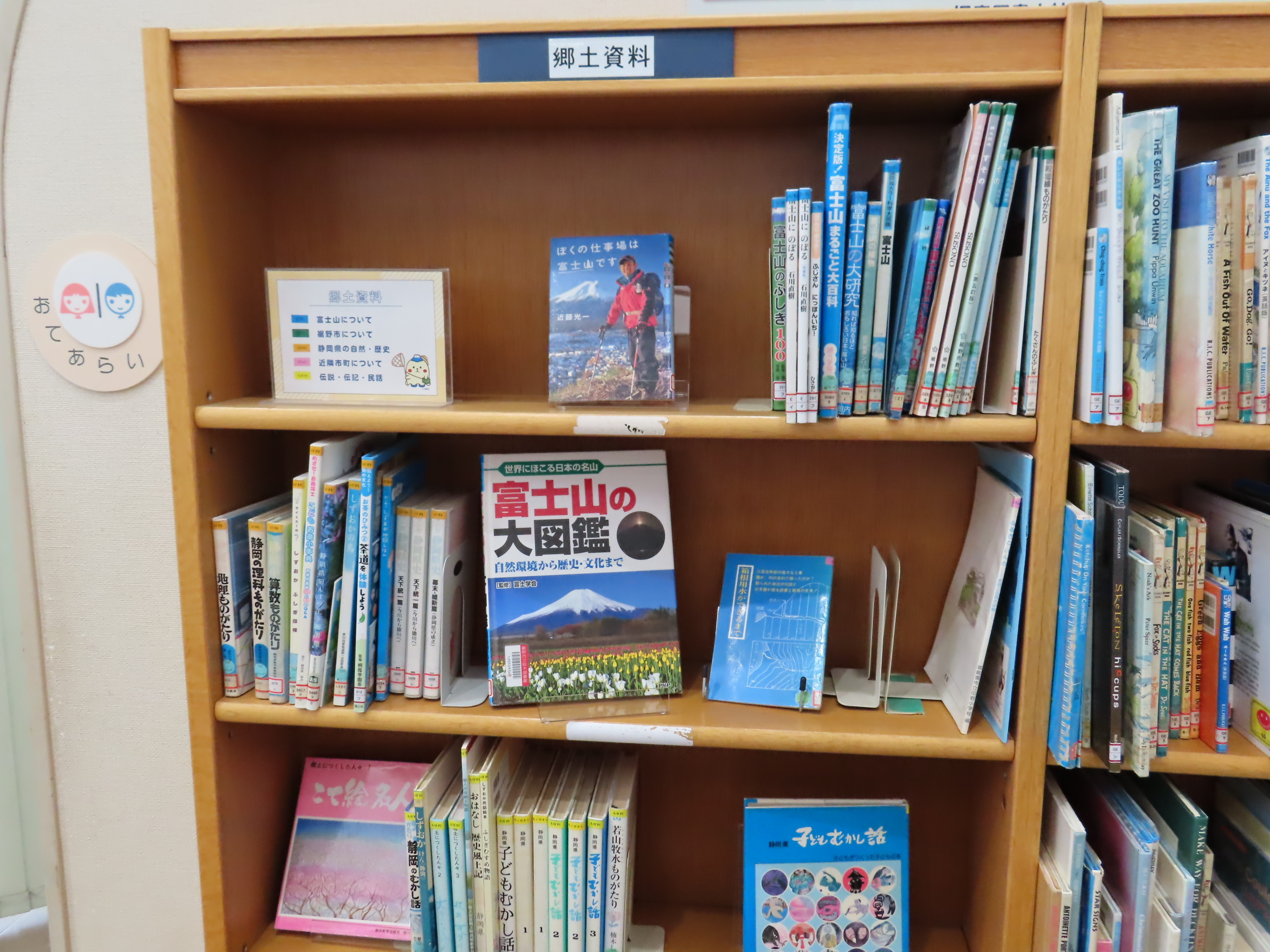 木製の本棚に郷土資料の表示と富士山の本を含む児童向けの図書が整然と並んでいる様子