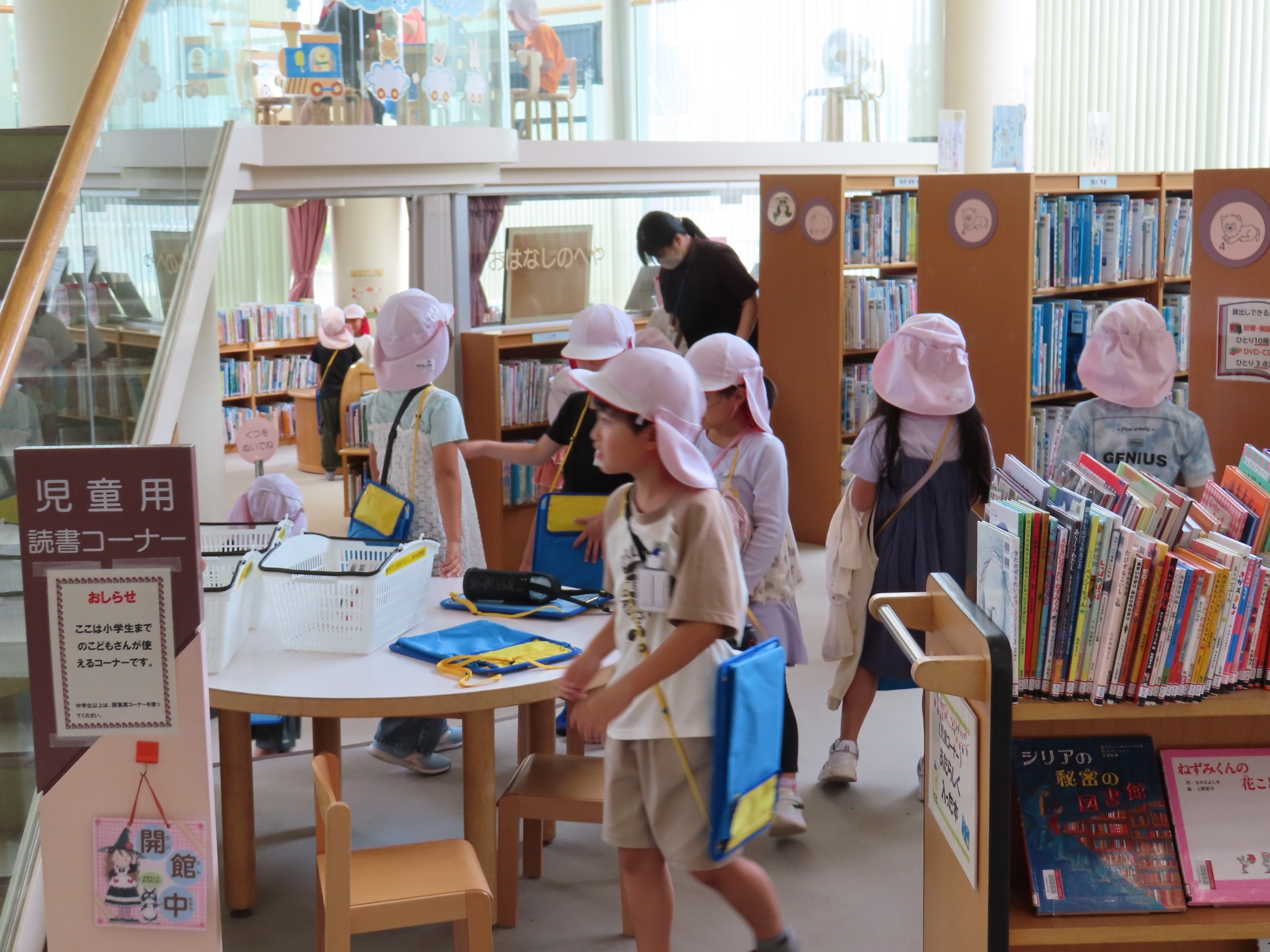 子どもたちが図書館の児童コーナーで本を選んだり机の周りを歩く様子