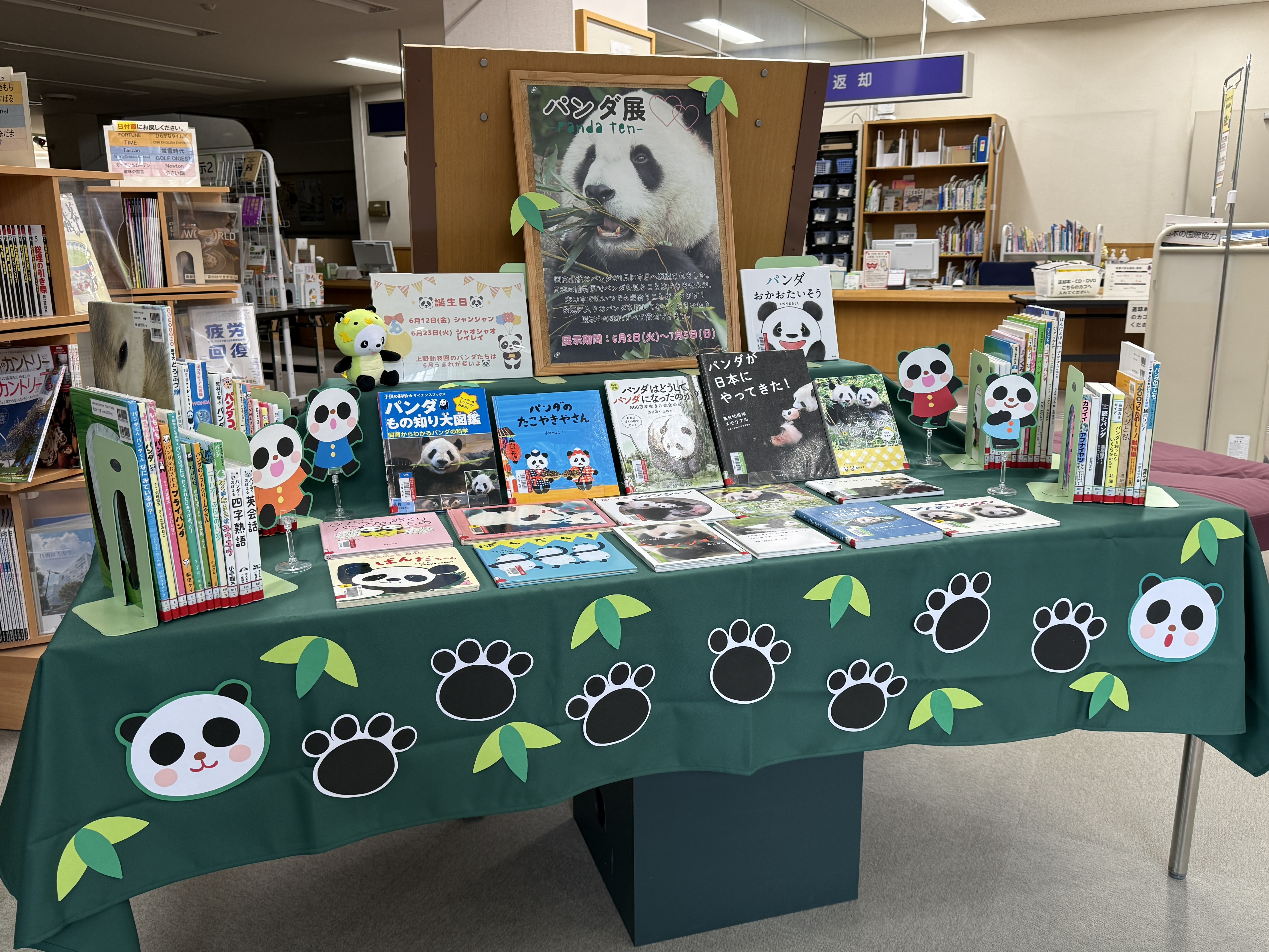 図書館の展示テーブルにパンダの大型ポスターやパンダの飾り付けがされた緑のクロスの上に絵本や図鑑が並べられている