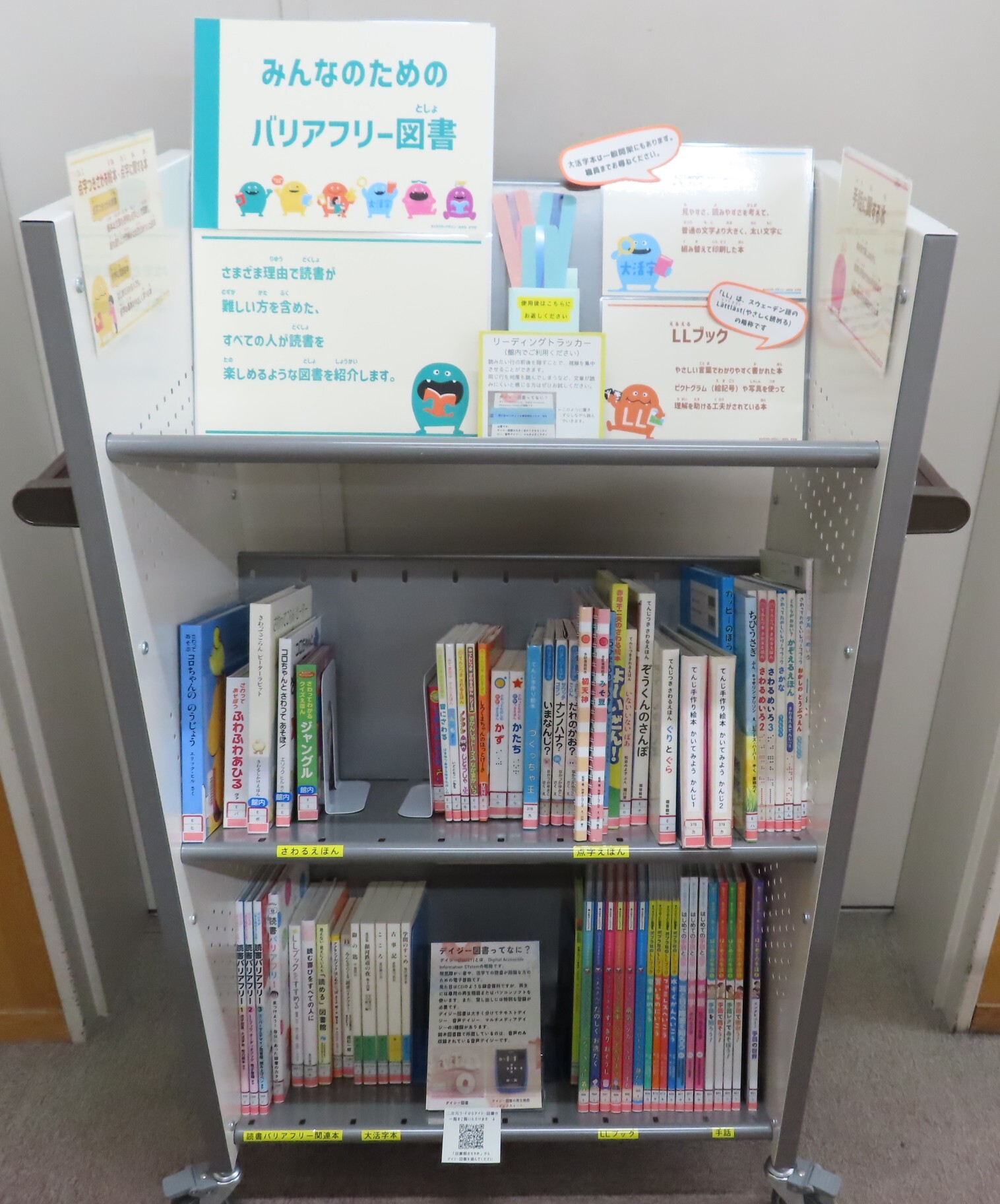 図書館の棚にバリアフリーに関する子ども向けと大人向けの本と案内表示が並んでいる
