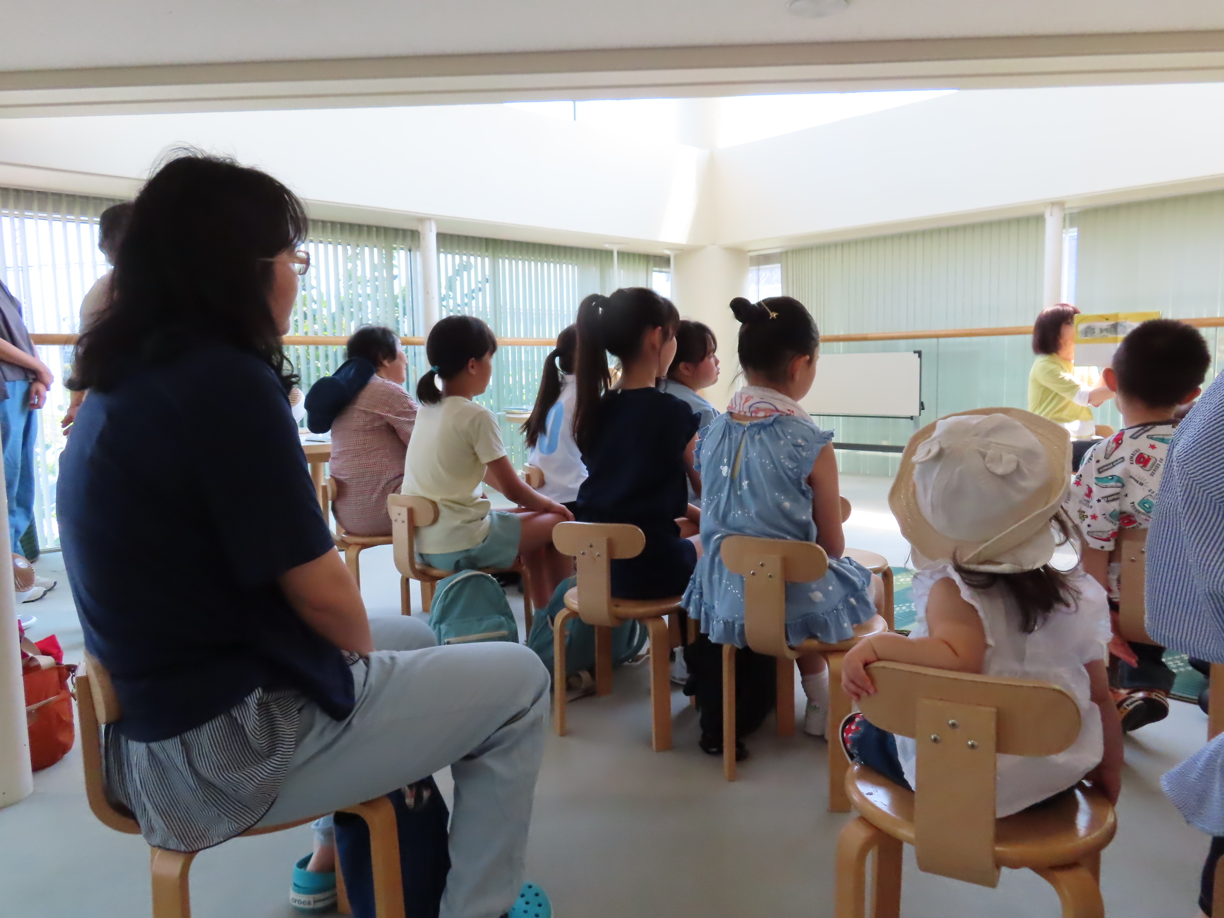 参加者が小さな椅子に座り絵本の読み聞かせを聞いている風景