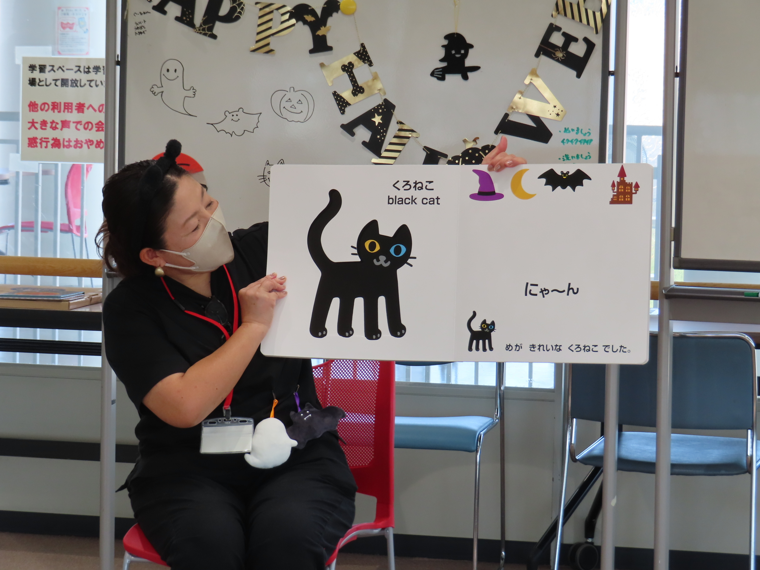 講師が大型絵本「ハロウィンのかくれんぼ」を読み聞かせしている