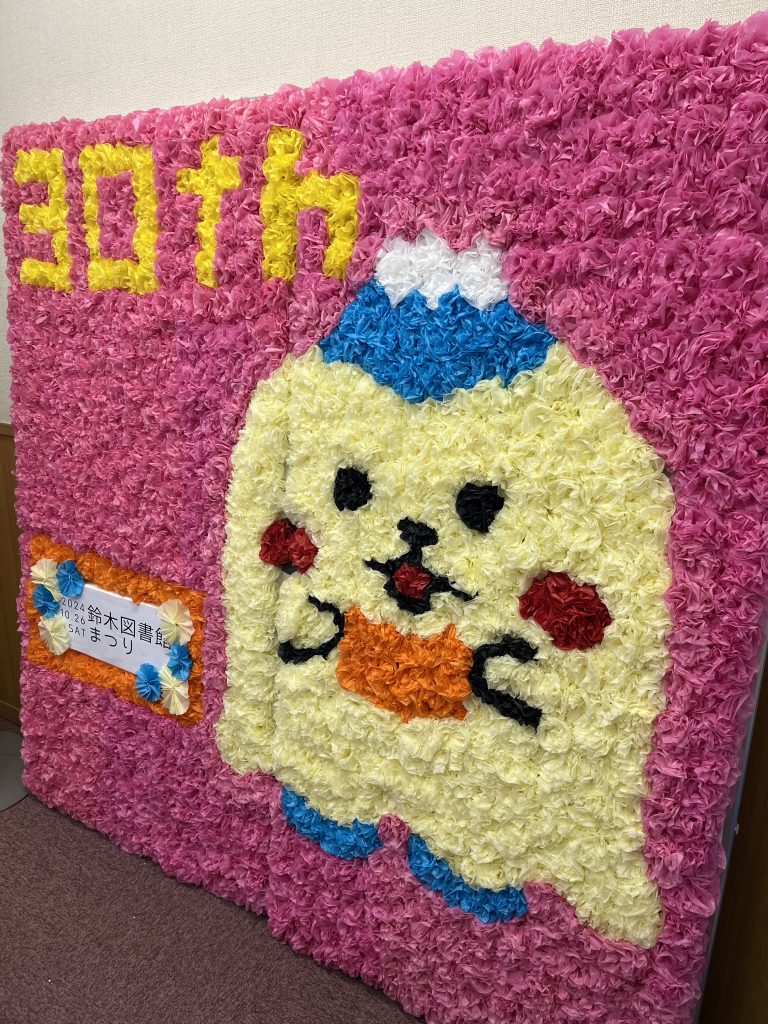 カラフルな花で作られたキャラクターのアート作品と「30th」と書かれた背景がある画像。