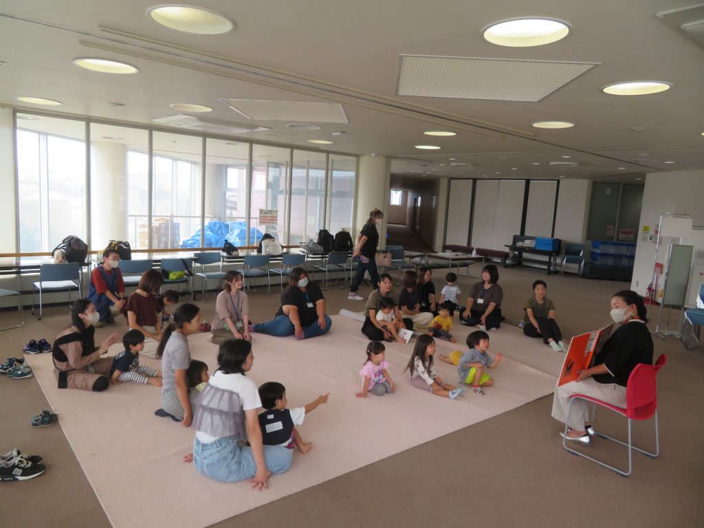 子供たちがピンクのマットの周りに座っている室内の様子