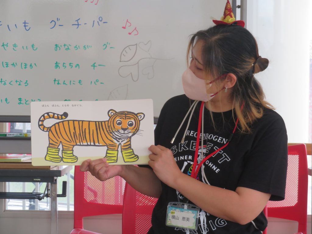 色とりどりの虎の絵を持っている人物が教室で何かを説明している様子