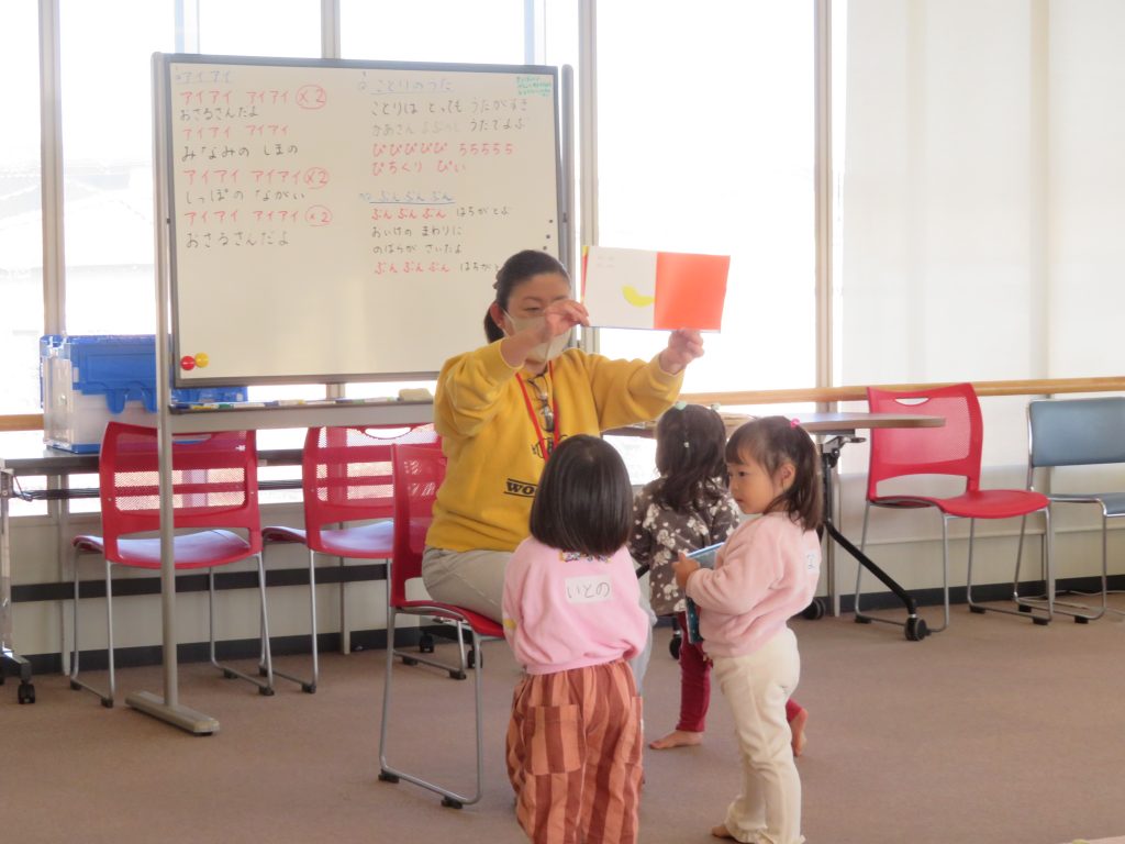 教室で指導者が子どもたちに色付きのカードを見せている場面