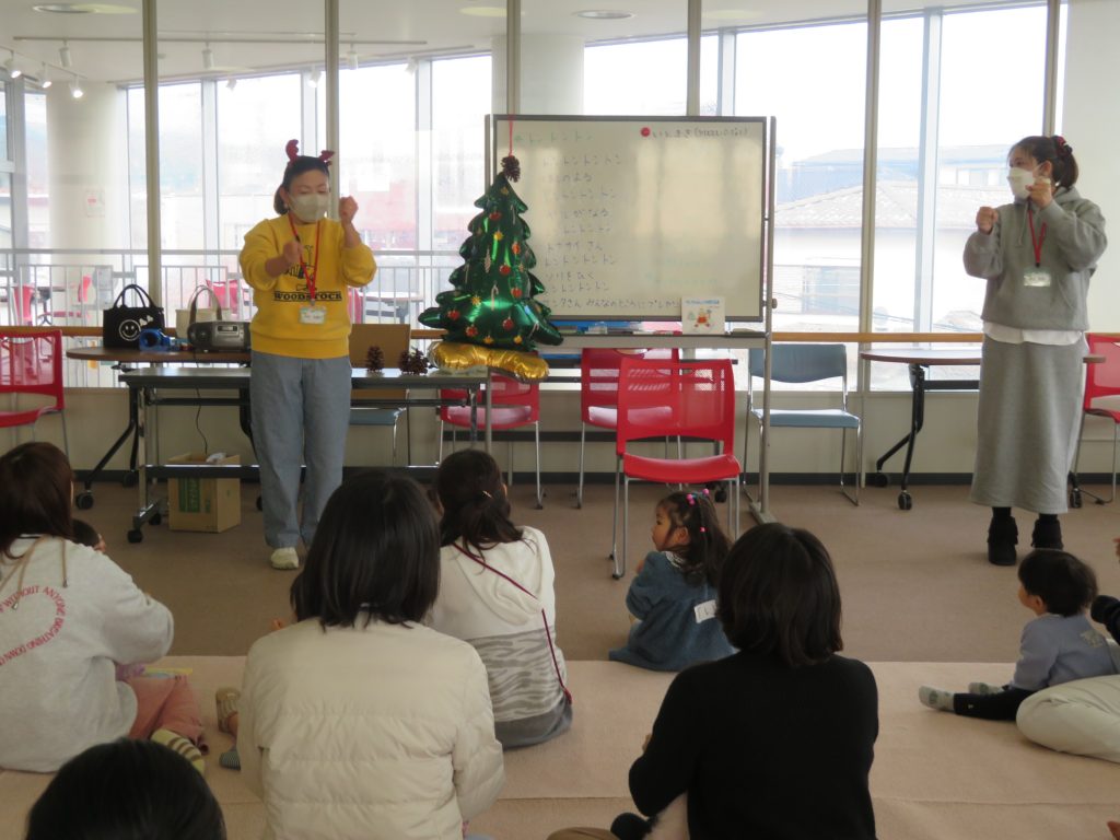 子供たちが座っている前で二人の大人が活動を行っている室内の様子