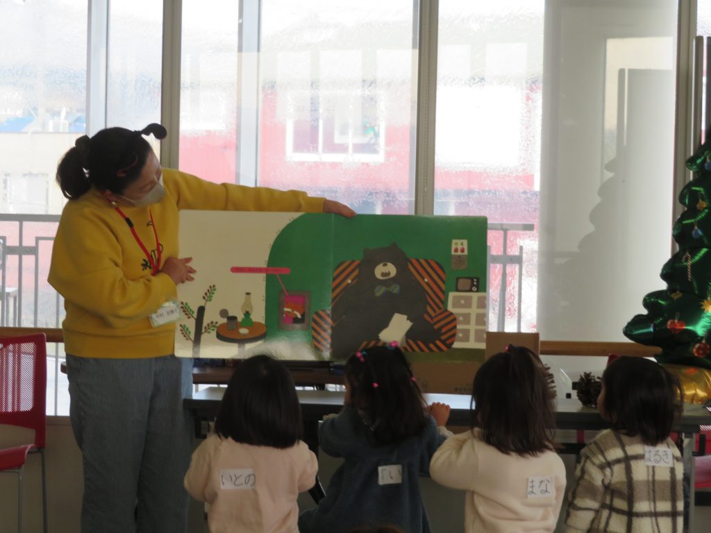 保育士が子どもたちに絵本を読み聞かせている場面。