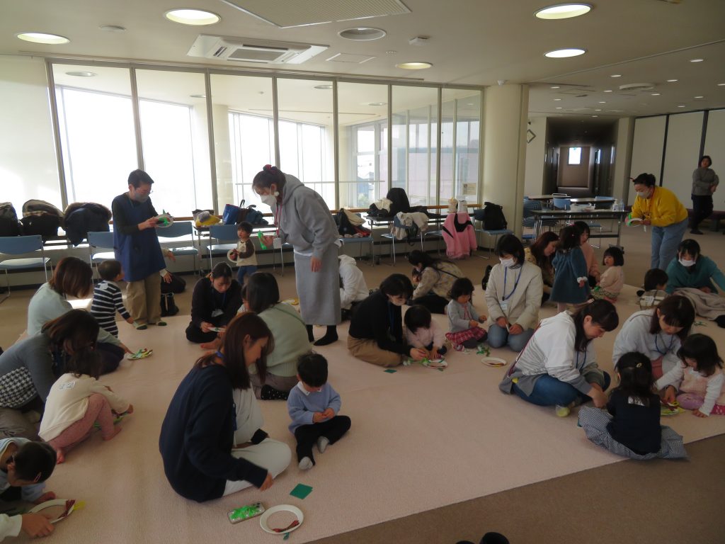 子供たちと大人が集まり、室内で活動している様子の画像です