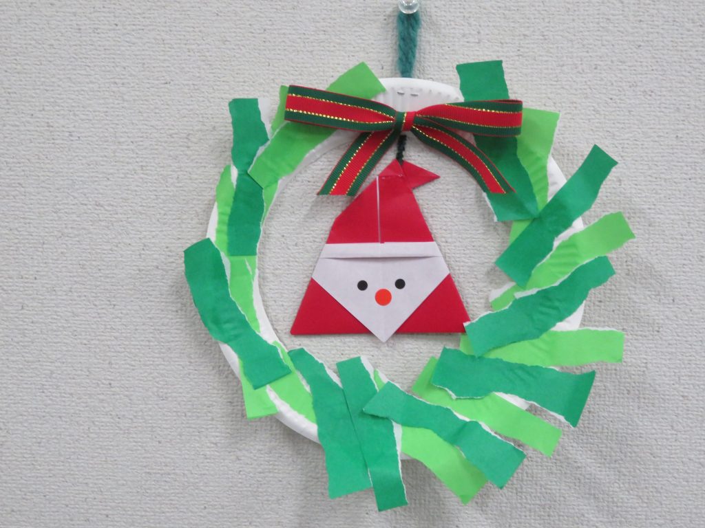 クリスマスリースに飾られたサンタの顔が描かれた飾り。