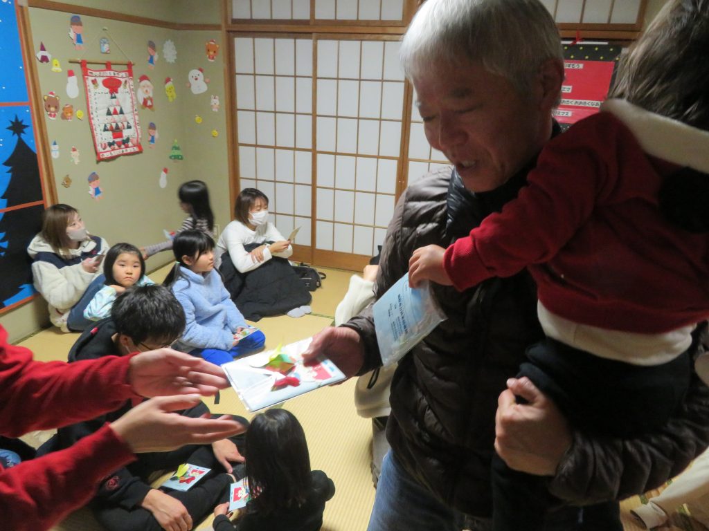 子供を抱えた大人が他の人に何かを渡している室内の様子