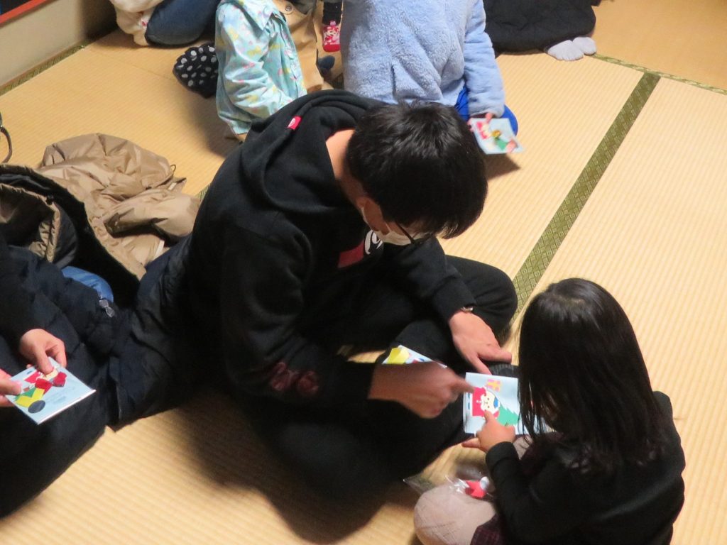 子供たちが床に座りながら色とりどりの紙を使って遊んでいる様子。