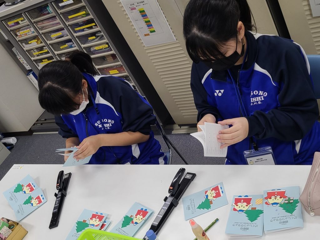 作業をしている二人の人物がテーブルの上で手作業を行っている様子が映っている。