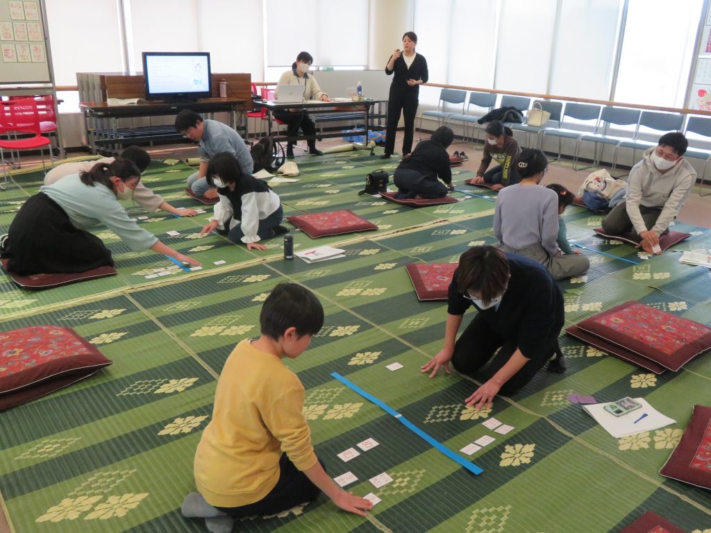 人々が室内のカーペットの上で作業をしている様子が描かれた画像。