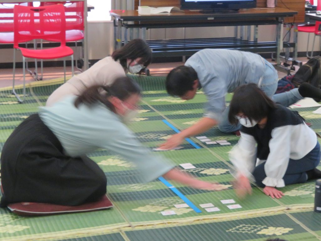 数人の人々が地面に広げられたカードを使って作業をしている様子。