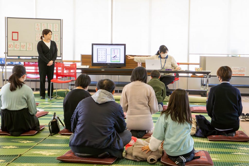 教室で講義を受ける学生たちと、講師がプレゼンテーションを行っている様子。