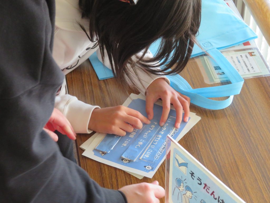 子供が机の上で青い紙に何かを書いている様子