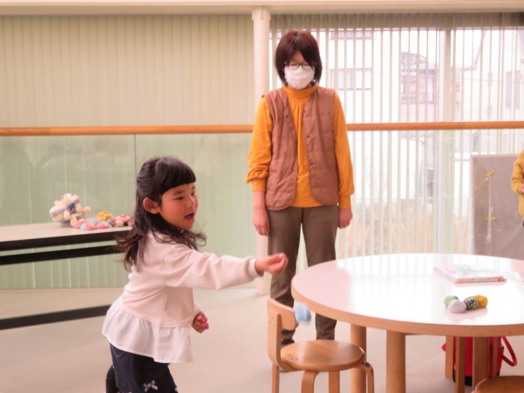 子供がテーブルに向かって手を伸ばしている場面と大人が立っている室内の様子。