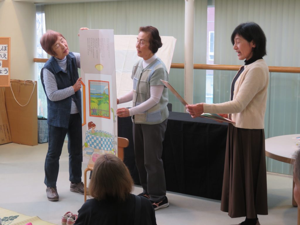 数人が掲示物を持っている室内の様子。