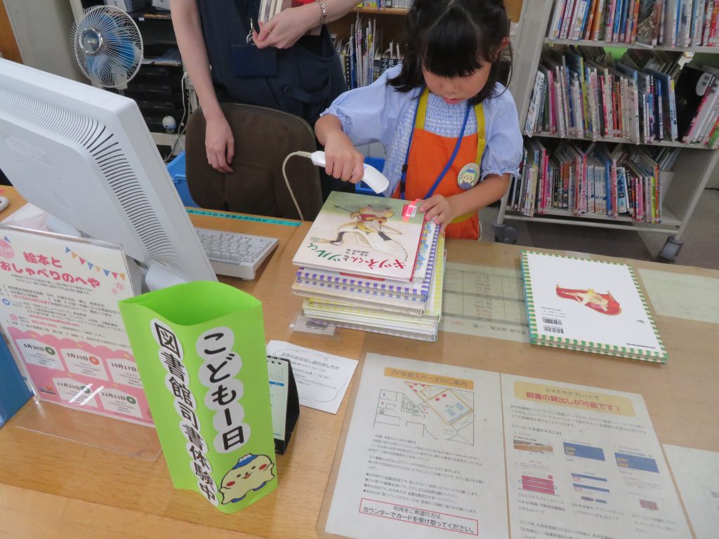 子供が机の上で絵を描いている様子と周囲に本や資料が置かれている画像。