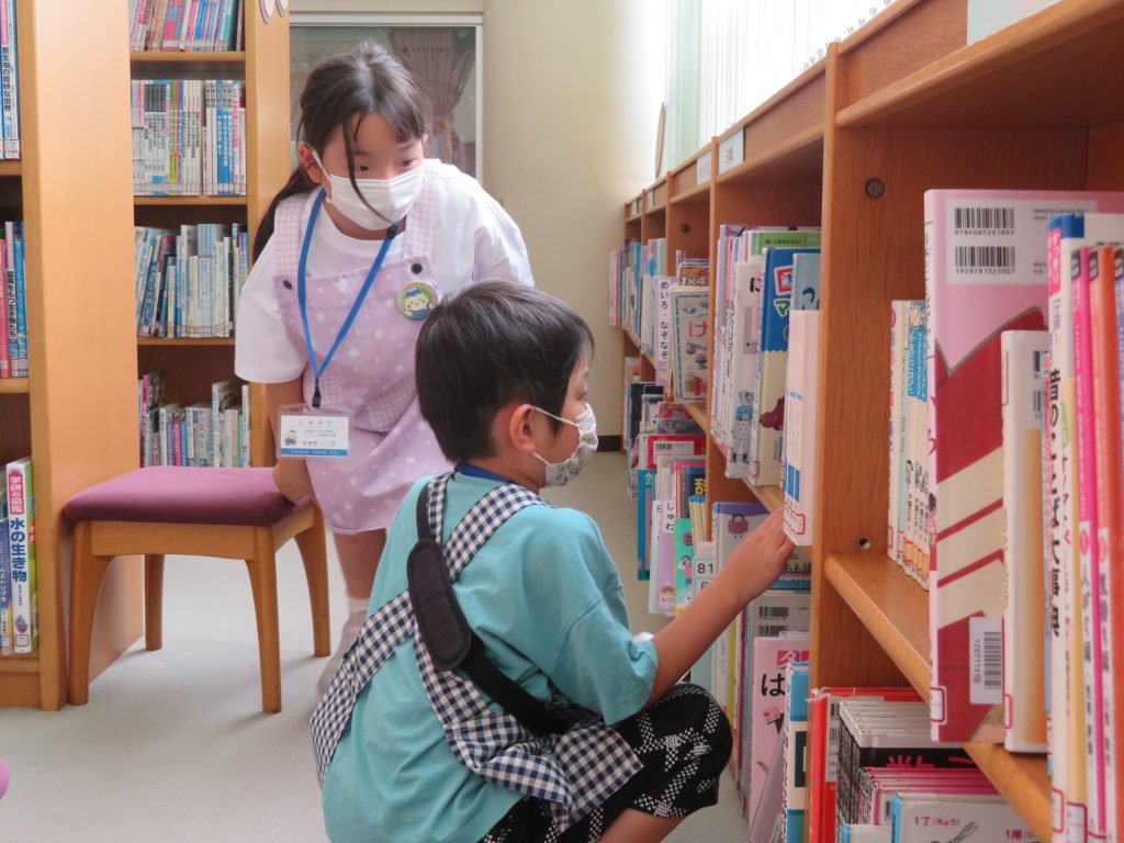 図書館で本を整理している子供と大人の様子