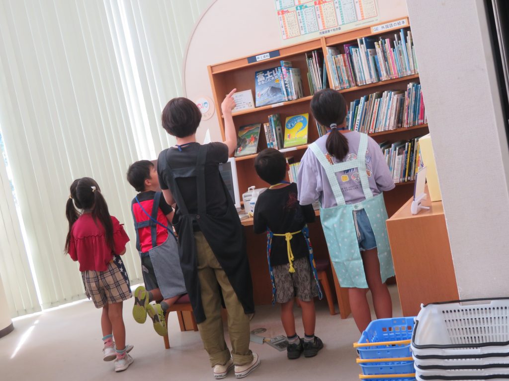 子供たちが図書館の本棚の前に立っている様子